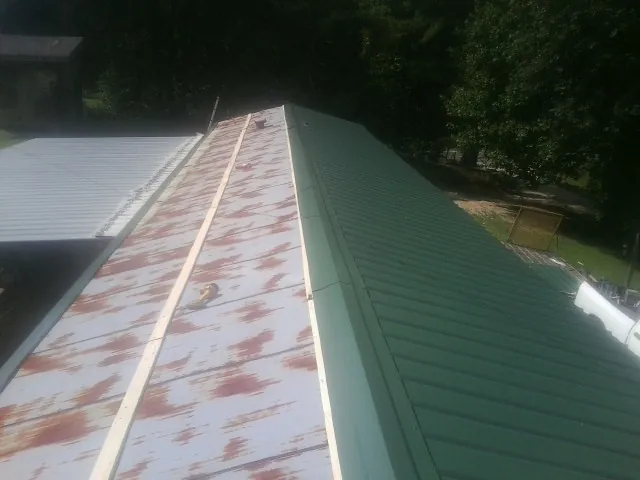 Old rusted panels beside newly installed green metal roofing — Wind Damage Roof Repair by Roofing Brothers in Morristown