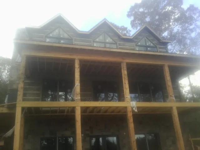 Dormers and porch framing on a large log home under construction — Roof Coating work by our crew in Morristown