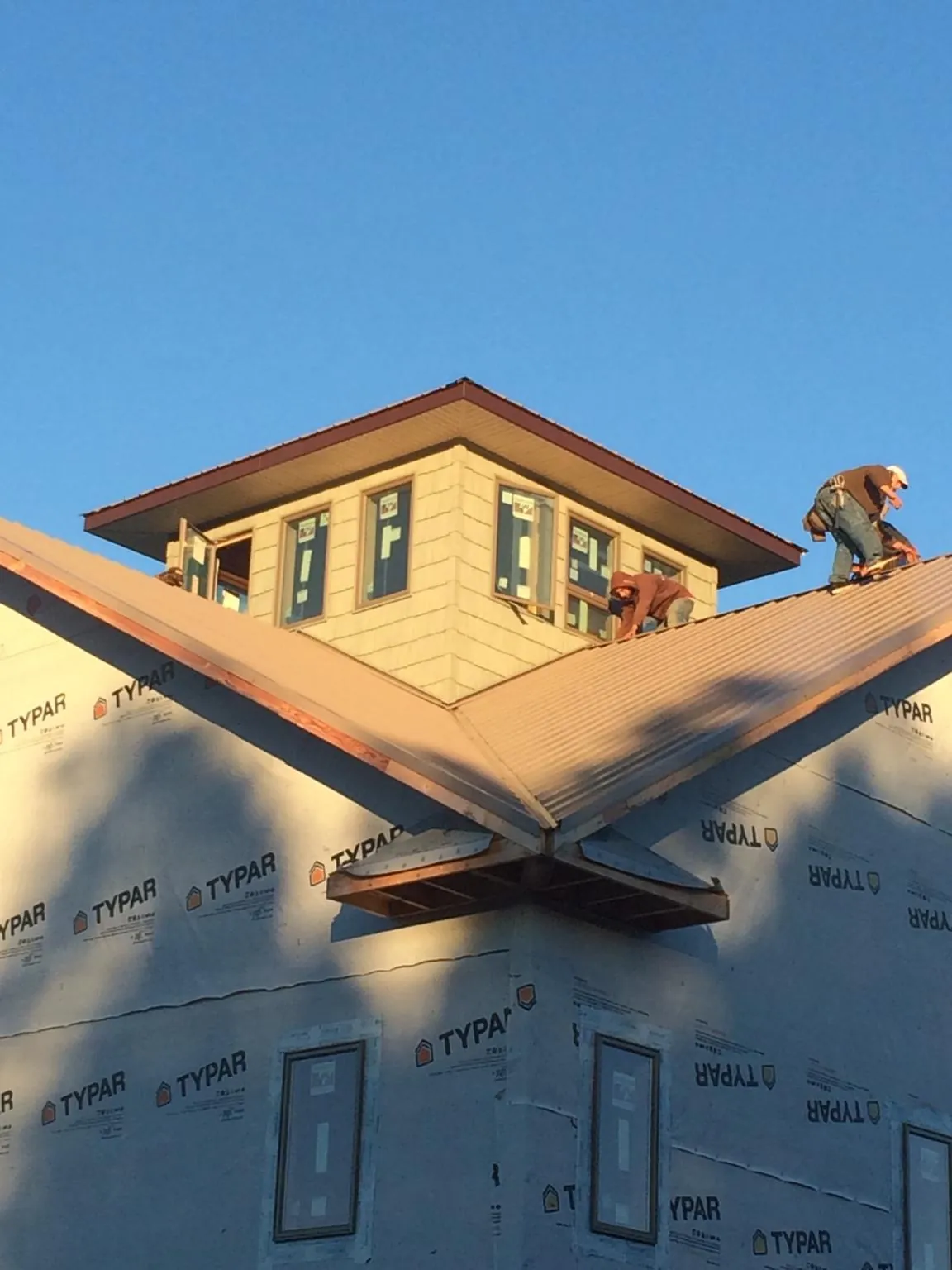 Roofers working around a rooftop cupola on a new metal roof at sunset — Roof Waterproofing in Morristown by Roofing Brothers
